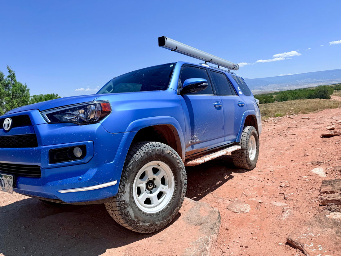 Blue 5th gen Toyota 4Runner on Falken Wildpeak A/T4W tires climbing a rocky trail