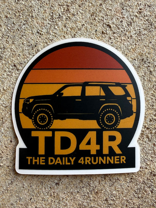 Die-cut vinyl sticker with a sunset arch design featuring a black 5th Gen 4Runner silhouette over yellow, orange, and red heritage stripes with TD4R text.